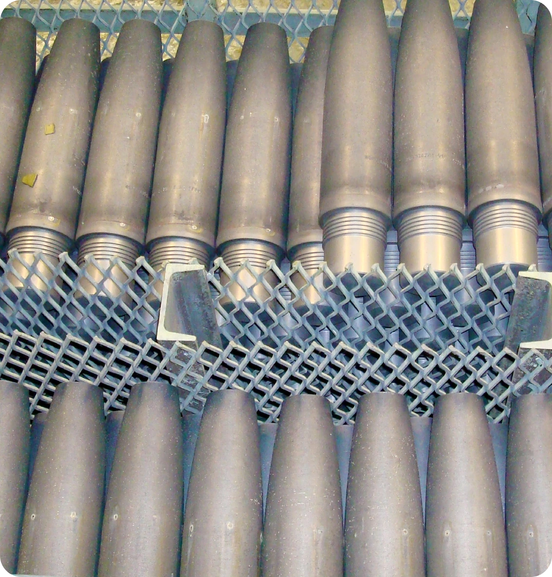 Rows of large artillery shells lined up on metal shelving.